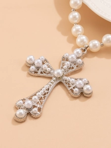 Detailed view of silver mesh cross pendant with embedded pearls on a necklace