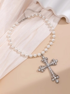 Detailed macro view of an ornate silver cross pendant with crystals on a pearl necklace