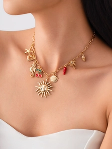 Dettaglio della collana dorata stile marino con ciondoli a stella marina, conchiglia e sole