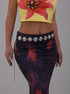 Detail of silver disc waist chain with spiral texture on floral print dress