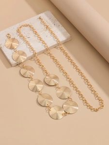 Detail of golden metal chain belt featuring textured circular discs on a stone background