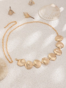 Detailed view of a gold-finish metal waist chain with seven textured scallop seashell charms