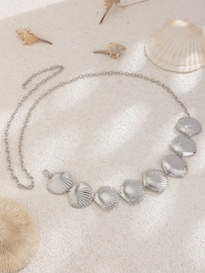 Macro shot of silver metal shell waist chain on a sandy background with corals