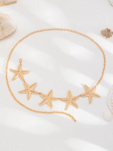 Detailed view of golden sea star waist chain with textured starfish on white sand