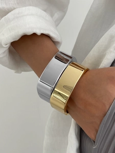 Gros plan de larges bracelets joncs minimalistes polis dorés et argentés sur un poignet