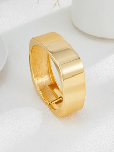 Gros plan d'un large bracelet doré avec finition polie et détail de la charnière à ressort
