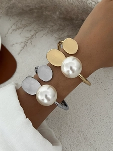 Detailed view of minimalist open cuff bracelets with large pearls in gold and silver finish