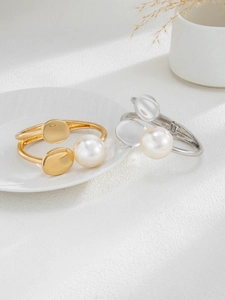 Detail of gold and silver irregular geometric pearl bracelets on ceramic display