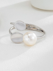 Detail of silver hinge bracelet with large pearl and asymmetric geometric oval charms