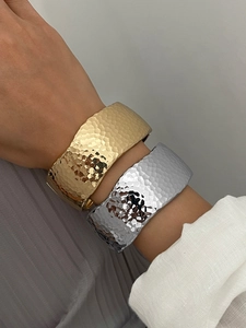 Macro shot of minimalist hammered texture on wide gold and silver cuff bracelets