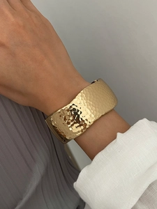 Detailed view of wide gold hammered cuff bracelet featuring unique textured light reflections