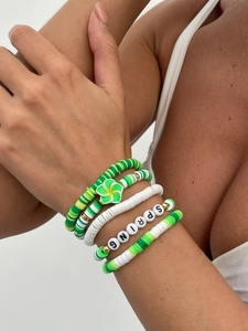 Nahaufnahme der Boho-Perlenarmbänder mit grüner Blume und SPRING-Buchstaben im Lagenlook