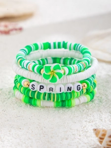 Detail von mehrlagigen Heishi-Armbändern mit grüner Blume und SPRING-Perlen