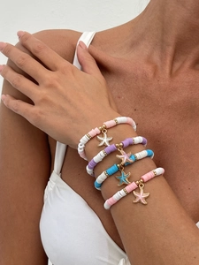 Set aus vier bunten Heishi-Perlenarmbändern mit Seestern-Anhängern am Handgelenk getragen