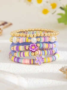 Detail bunter Boho-Armbänder mit Perlen und lila Blumenanhängern im mehrlagigen Set