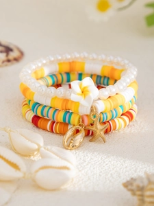 Detail von bunten Polymer-Ton-Armbändern mit goldenen Muschel- und Seesternanhängern