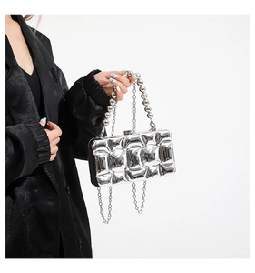 Close-up of silver quilted puffer acrylic clutch bag with metallic beads handle chain