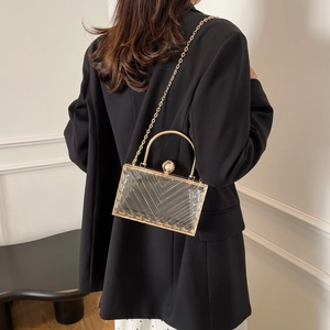 Detailansicht einer transparenten Acryl-Clutch mit V-Struktur und goldener Kette