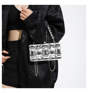 Silver metallic acrylic clutch bag with quilted texture and decorative bead handle