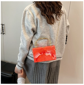 Detail of orange marble acrylic box bag with gold handle and metal chain strap