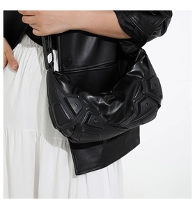 Dettaglio della borsa a tracolla nera futuristica con texture 3D geometriche su modella