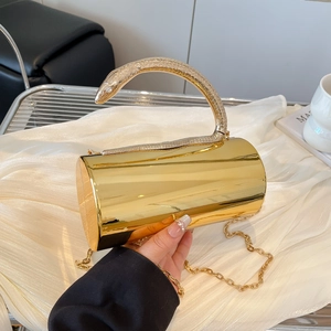 Detail of gold cylindrical evening bag with snake-shaped metal handle and rhinestone eyes