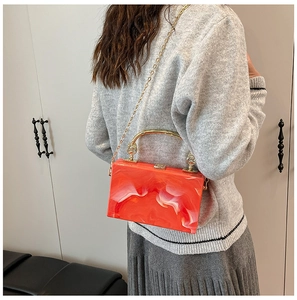 Detail shot of orange marble acrylic box bag with gold U-shaped handle and chain strap