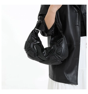 Dettaglio della borsa hobo nera con pannelli geometrici a rilievo e finitura strutturata
