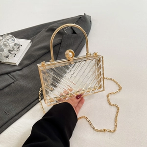 Detail der transparenten Acryl-Clutch mit V-Struktur und goldenem Metallgriff