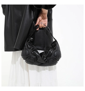 Dettaglio borsa a mano nera minimalista in pelle con struttura 3D e design geometrico