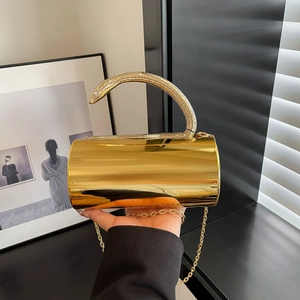 Detailed macro of golden cylindrical evening bag with snake handle and metallic chain