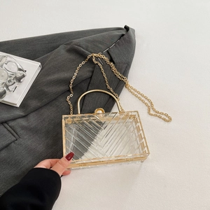 Detail der transparenten Acryl-Abendtasche mit Goldrahmen und elegantem Perlenverschluss