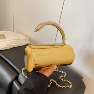 Close-up of golden cylindrical evening clutch featuring a detailed snake-shaped handle