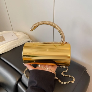 Detailed close-up of golden cylindrical evening clutch featuring a snake-shaped handle