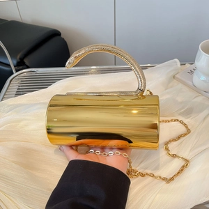Detailed view of golden cylindrical clutch bag with luxury serpent handle and chain