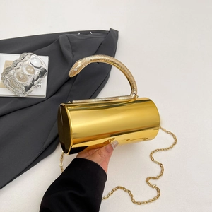 Detail of mirror gold cylindrical clutch with textured snake handle and gold chain strap