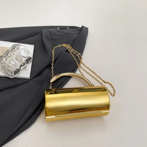 Close-up of golden cylindrical evening clutch with snake handle and metallic chain strap