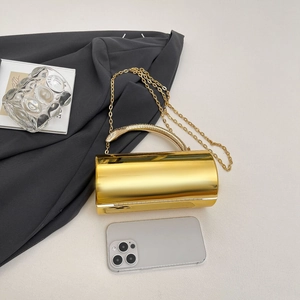 Detailed view of a gold cylindrical evening bag featuring a unique snake-shaped handle