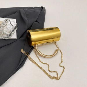 Detail of gold mirror cylinder clutch featuring a snake handle and metal chain strap