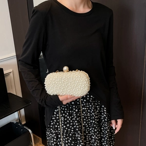 Detailed view of pearl evening bag with ornate pearl clasp and golden chain strap