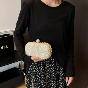 Detail of elegant handmade pearl evening clutch bag with gold frame and chain strap