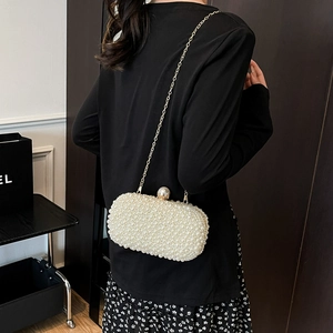 Elegant white pearl clutch evening bag with gold chain strap shown on black dress