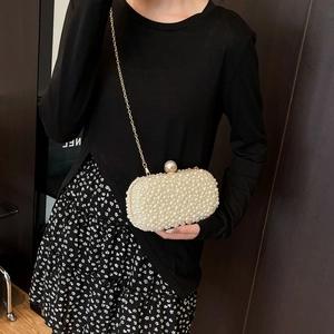 Detail of elegant handmade pearl evening clutch with gold chain and large pearl clasp