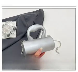 Pochette cylindrique argentée mate avec poignée élégante et détail de chaîne en métal
