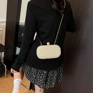Elegant pearl evening clutch bag with gold chain strap worn by a model in a formal setting