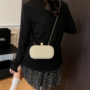 Detail of elegant handmade pearl clutch bag with gold chain strap and large pearl clasp
