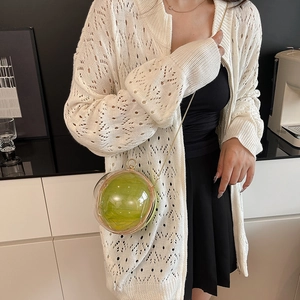 Chic spherical crossbody bag with green lining and gold chain shown on a model