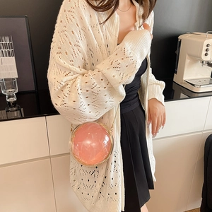 Pink translucent sphere handbag with golden chain strap shown in a modern lifestyle setting