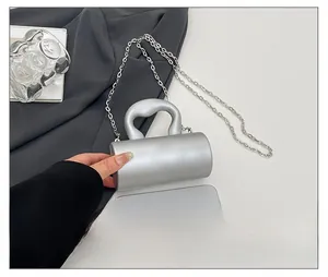 Comparaison de taille du sac cylindrique argenté avec smartphone et chaîne métal