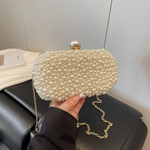 Detail of handmade pearl evening clutch bag with gold chain and large pearl clasp